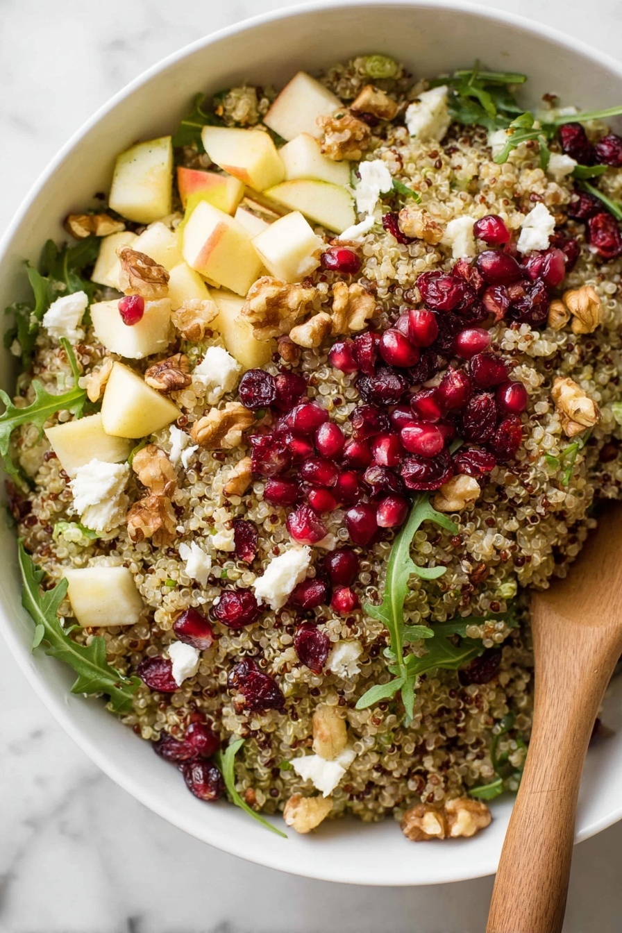 A white bowl filled with a quinoa salad that has three main layers; the bottom layer is light tan quinoa grains, the middle layer has small chunks of light yellow apples, scattered red pomegranate seeds, dark red dried cranberries, and white crumbled cheese, while the top layer has a few green arugula leaves and some walnut pieces. A wooden spoon rests on the right side of the bowl, partially inside the salad. Around the bowl, there are scattered pomegranate seeds, green arugula leaves, and some quinoa grains on a white marbled surface. In the top left corner, there are a few open pomegranate halves with red seeds visible. photo taken with an iphone --ar 2:3 --v 7
