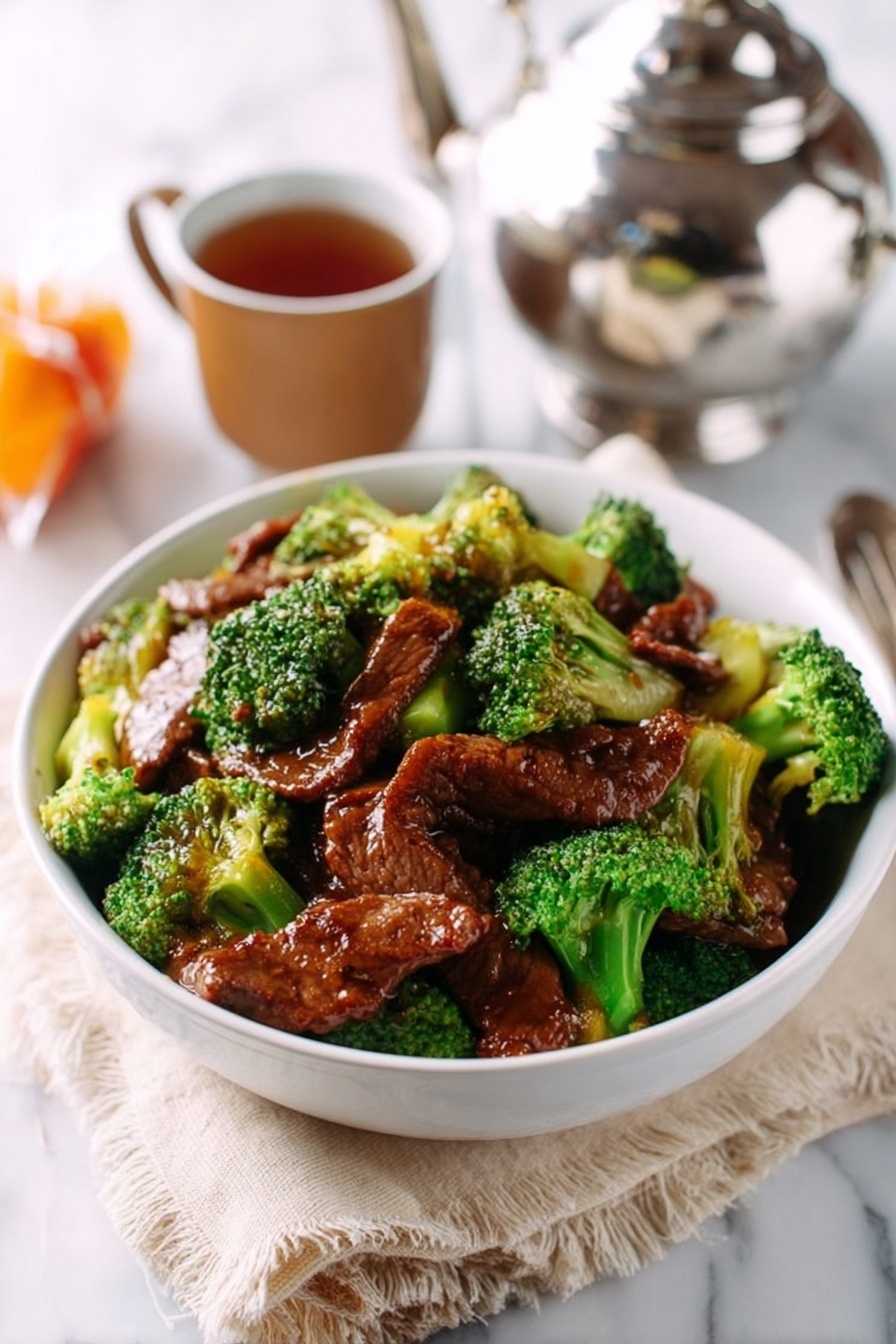 A white bowl filled with layers of bright green broccoli florets and stems, mixed with several pieces of glossy, brown cooked meat on top. The broccoli looks fresh and crunchy, while the meat is thick and shiny with sauce. The bowl is placed on a light beige cloth on a white marbled surface. In the background, there is a shiny silver metal teapot, a brown cup, and a wrapped orange snack. Photo taken with an iphone --ar 2:3 --v 7