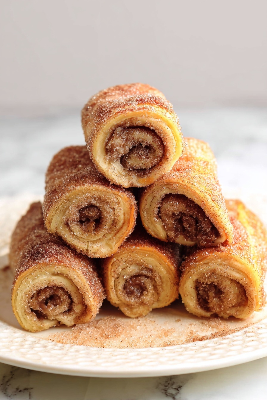 The image shows six rolled pastries stacked in a pyramid shape on a white plate, placed on a white marbled surface. Each roll has a golden brown outside coated with visible sugar and cinnamon, giving a textured, slightly crispy look. Inside, the layers are swirled tightly with a darker cinnamon filling visible in the center. The rolls have a soft, slightly fluffy appearance with some sugar crystals scattered around them on the plate. Photo taken with an iphone --ar 2:3 --v 7