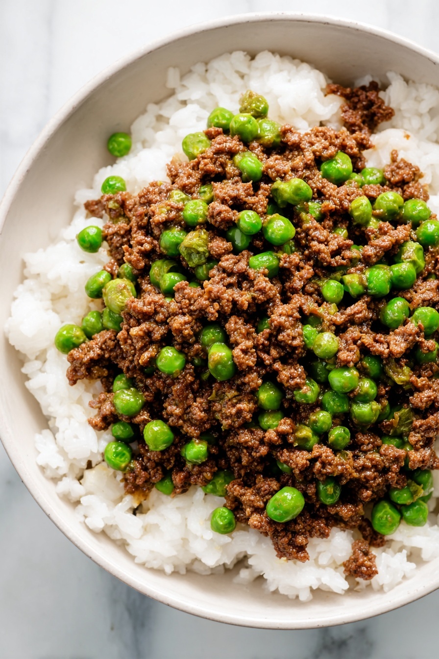 A white round plate holds two main layers. The bottom layer is fluffy white rice with separate grains, filling the whole plate. On top, there is a layer of brown ground meat mixed with bright green peas scattered evenly. The meat looks crumbly and slightly moist, while the peas are round and shiny, creating a colorful contrast with the white rice below. The plate sits on a white marbled surface, giving a clean and bright background. photo taken with an iphone --ar 2:3 --v 7