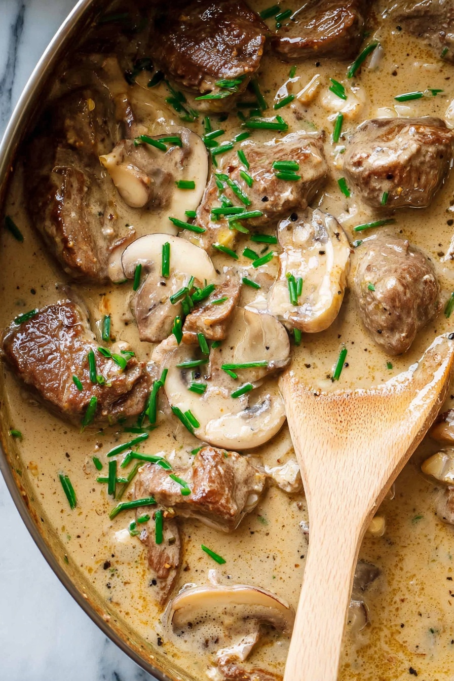 A close-up view of a creamy beige sauce with a smooth and slightly thick texture, covering several pieces of brown cooked meat that sit alongside slices of light brown mushrooms. The sauce and meat pieces are sprinkled with small, bright green chopped herbs, adding contrast. A wooden spoon with a warm natural wood tone rests on the right side, partially submerged in the sauce. The dish is shown on a white marbled surface. photo taken with an iphone --ar 2:3 --v 7